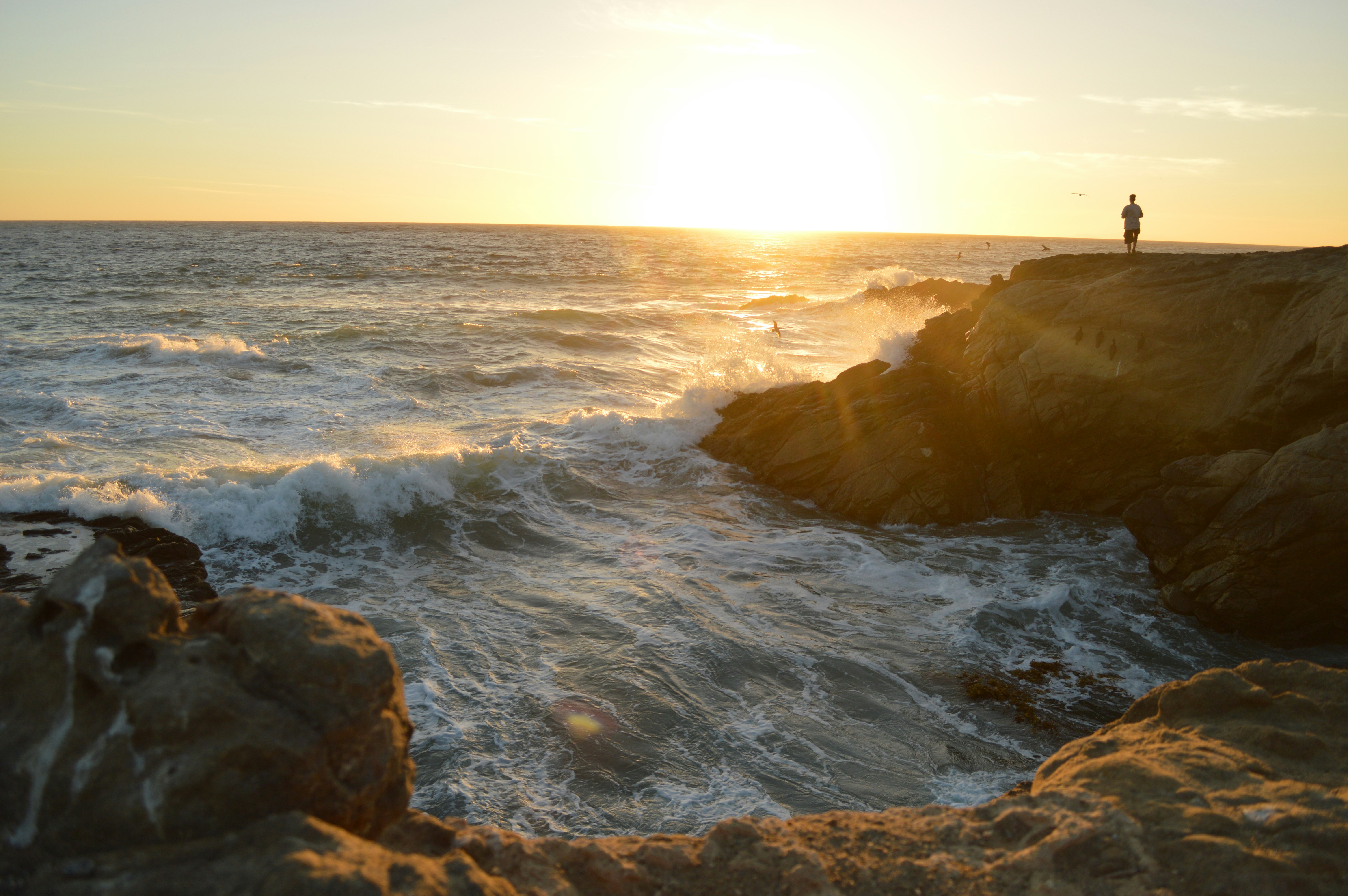 person on rock formation during sunset